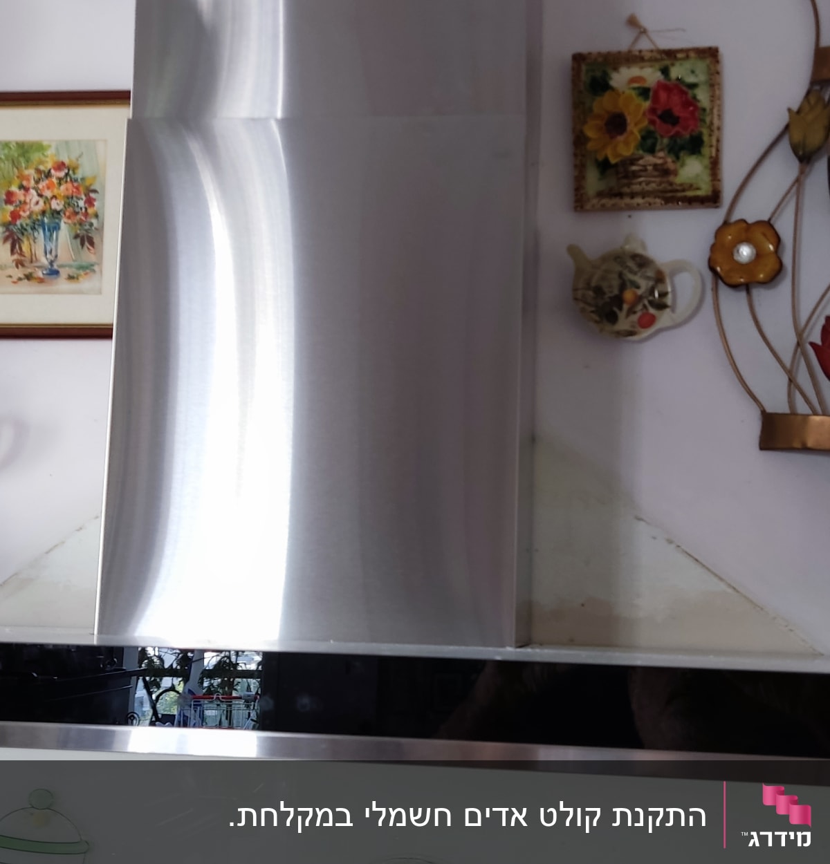 קולט אדים נירוסטה במטבח עם קישוטים על הקיר